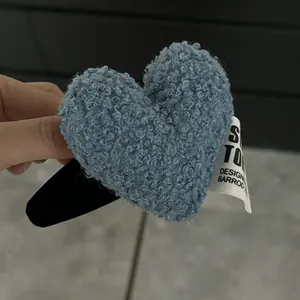 Gros plan sur une pince à cheveux cœur en peluche bleue avec étiquette en tissu blanc