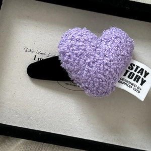 Vue macro d'une pince à cheveux cœur en peluche violette avec texture douce en laine d'agneau