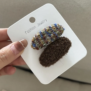 Dettaglio del set di fermagli per capelli in tweed multicolore e peluche marrone