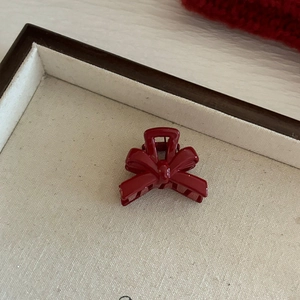 Pince à cheveux rouge brillante en forme de nœud sur plateau avec décor festif