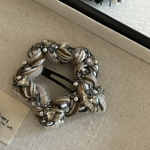 Retro knitted hair clip with sparkling rhinestones and pearls on a textured background
