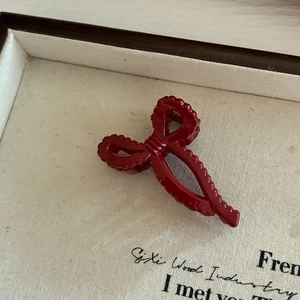 Gros plan d'une pince à cheveux nœud rouge foncé avec texture ondulée de style rétro