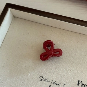 Vue détaillée d'une petite pince à cheveux nœud rouge foncé dans un plateau en bois