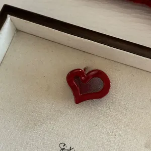 Gros plan d'une petite pince à cheveux rouge en forme de cœur sur un plateau d'exposition beige