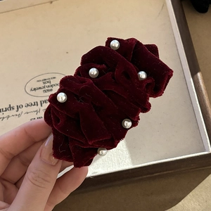 Macro detail of wine red velvet hair clip with delicate pearls and pleated texture