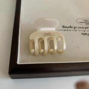 Elegant cream acetate hair claw clip with golden label for French style updo hairstyles