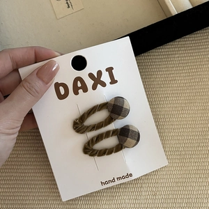 Detail view of brown velvet hair clips with checkered buttons on a display card