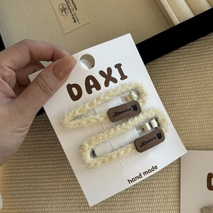 Detail of hand-woven beige bow hair clips for girls with cute bear embroidery on card