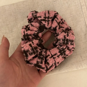 Detailed texture of pink and brown houndstooth tweed scrunchie on linen fabric