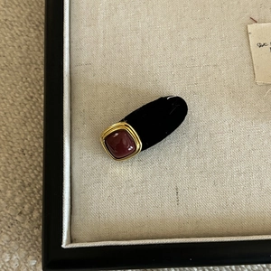 Detail of red velvet hair clip with a square gemstone inlay and gold metal trim