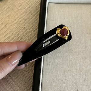 Detailed close-up of a vintage black velvet BB hair clip with a red heart gem accent
