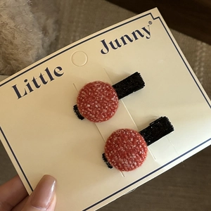 Pair of red tweed round hair clips with classic woven texture and black fabric lining
