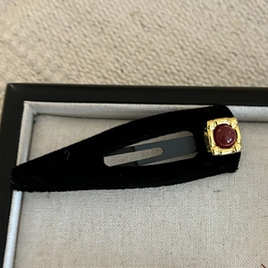 Detail of a red gemstone on golden base with black velvet flocking hair clip