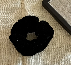 Gros plan sur un chouchou en velours noir montrant la texture douce et le design plissé