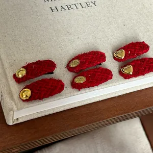 Detail of six red tweed hair clips with vintage gold metal buckles on a linen book
