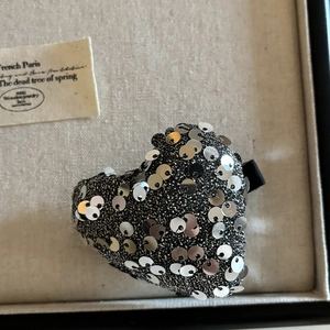 Détail d'une barrette en forme de cœur avec paillettes argentées et pince crocodile noire
