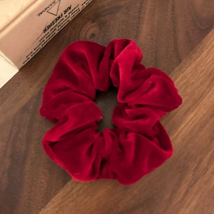 Détail de l'élastique en velours rouge foncé avec plis sur une table en bois