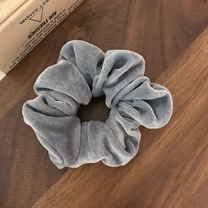 Gros plan d'un chouchou en velours bleu gris avec plis doux sur bois sombre
