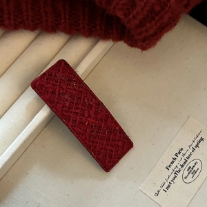 Close-up of a burgundy tweed fabric rectangular hair clip with a textured woven pattern