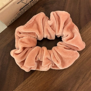 Chouchou en velours orange corail sur fond bois avec accessoires esthétiques déco