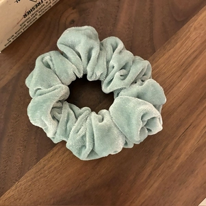 Chouchou en velours vert menthe avec texture plissée douce sur fond en bois