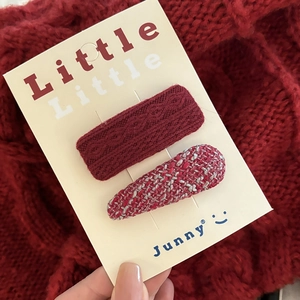 Detail of red knitted and tweed hair clips set on display card over cozy sweater