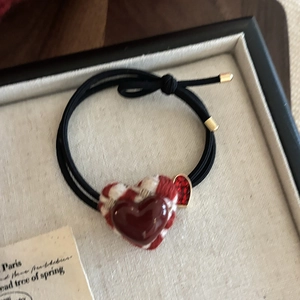 Durable elastic red heart hair tie with plaid and glitter details on a tray