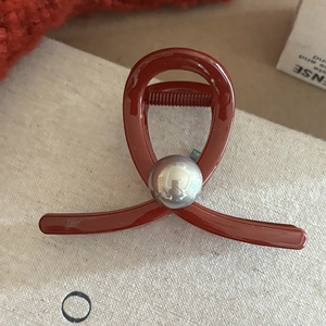 Pince à cheveux rouge brique élégante avec finition brillante et détail de sphère métallique
