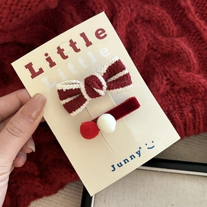 Detail of red knitted bow and plush ball hair clips set on a display card for New Year