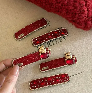 Détail de cinq barrettes rouges à strass avec breloques dorées et finition pailletée