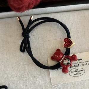 Elastic black hair tie featuring a heart crystal charm and a red enamel bear pendant