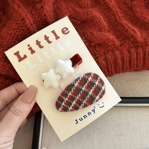 Detail of red velvet star hair clips and plaid duckbill hairpins on a knit background