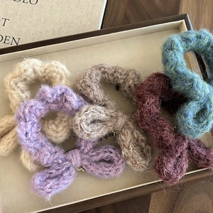 Chouchous en peluche tricotée avec nœuds en couleurs automnales sur plateau bois