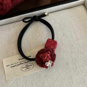 Detailed shot of elastic hair tie with red rhinestone cube, plush ball and resin bear