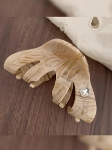 Detail view of acetate shark hair clip with marble texture and crystal inlay