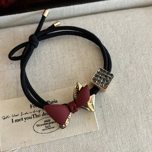 Close-up of a burgundy bow hair tie with sparkling rhinestone and gold metal accents