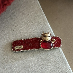 Barrette en strass rouges avec détail de dragon doré sur fond de lin gris clair