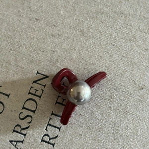 Gros plan d'une pince à cheveux rouge foncé en forme de nœud avec perle argentée