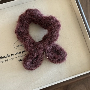 Gros plan sur un chouchou en laine rouge foncé avec une texture douce et bouclée