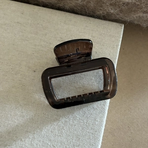 Vue détaillée d'une grande pince à cheveux marron foncé transparente avec ressort