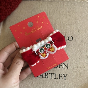 Detail of red velvet bow hair clip with embroidery and white plush pom-poms