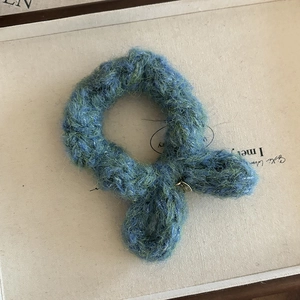 Détail d'un chouchou en laine tricotée avec oreilles de lapin et pendentif doré