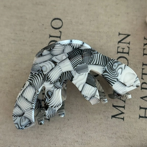 Detailed macro view of a black and white marbled acetate hair claw with metal spring