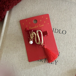 Close-up of red velvet hair clip with dragon embroidery and silk tassels on card