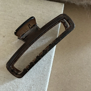Détail d'une grande pince à cheveux rectangulaire marron foncé translucide avec ressort