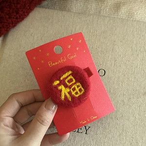 Detailed embroidery of a golden Fu character on a red plush Chinese New Year hair clip