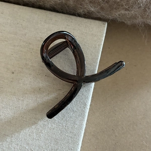 Vue détaillée d'une pince à cheveux torsadée en résine ambrée montrant les dents de fixation