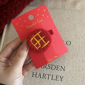 Close-up of red plush hair clip with yellow Wang character embroidery for Chinese New Year