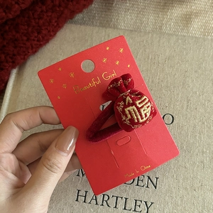 Detail of red velvet hair clip with gold embroidered lucky bag and Fu character
