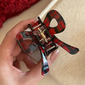 Close-up of a red and black plaid butterfly hair claw clip with hollowed-out wings